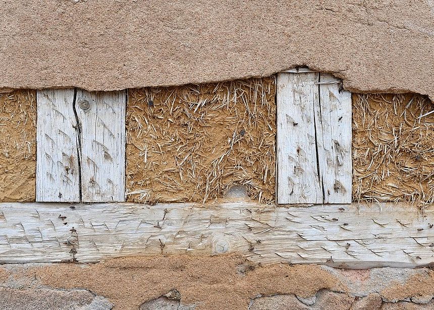 Hauswand aus Holzbalken, Stroh und Lehm Hauswand aus Holzbalken, Stroh und Lehm